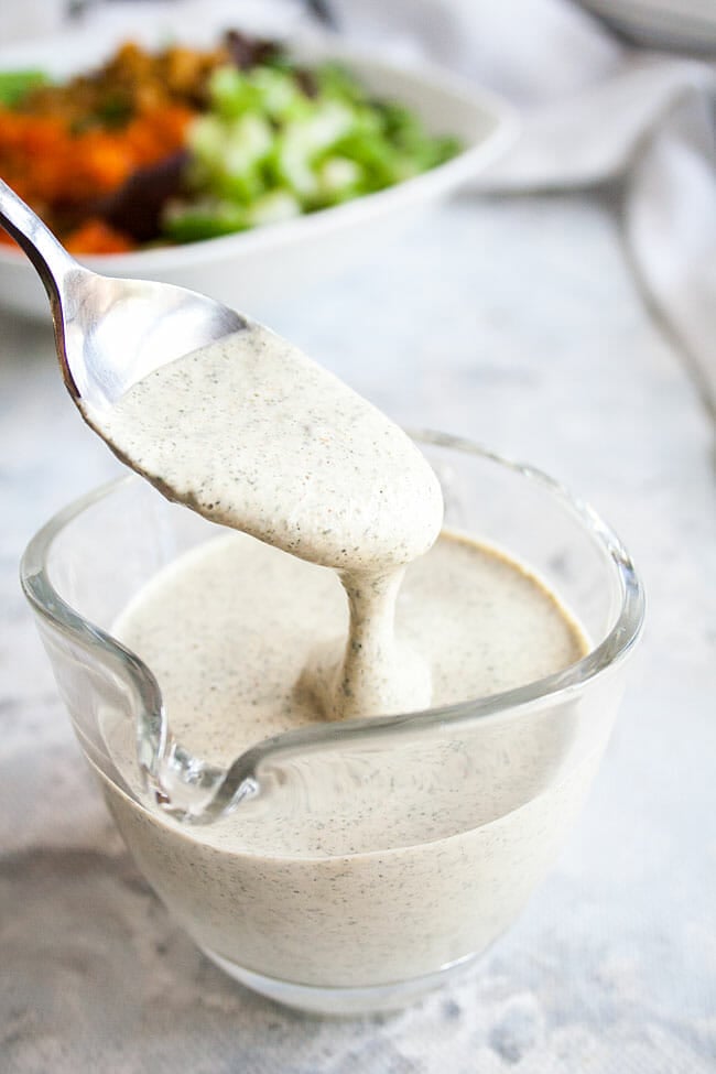 Spoonful of Hemp Ranch Dressing with salad in the background. 