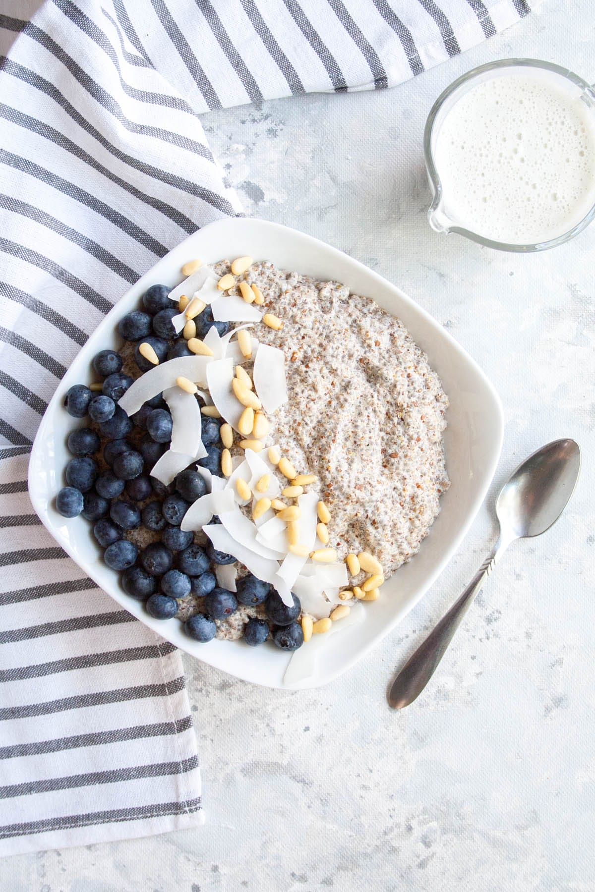 Spiced Chia Seed Porridge (vegan, gluten free, sugar free, keto) - This hearty breakfast is a a great way to start your day. It takes only minutes to make! #chiaseedporridge #veganketo #ketorecipes #ketobreakfast Spiced Chia Seed Porridge with a spoon and hemp milk in a pitcher.