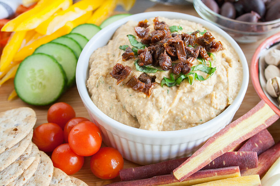 Sun-Dried Tomato and Basil Hummus with vegetables, olives, and crackers.