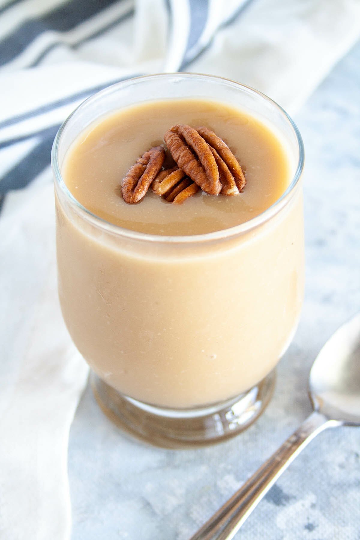 Vegan Butterscotch Pudding in a jar with pecans on top.