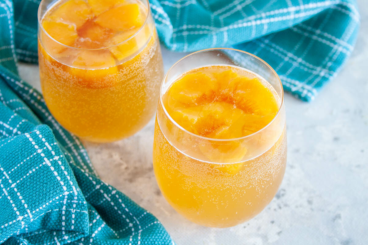 Peach Kombucha in two wine glasses close up.