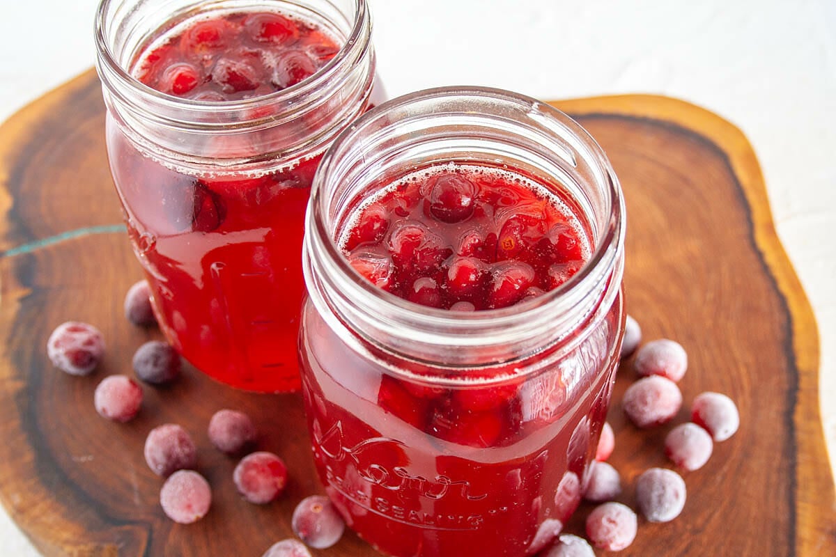 Cranberry Kombucha in mason jars on cutting board.