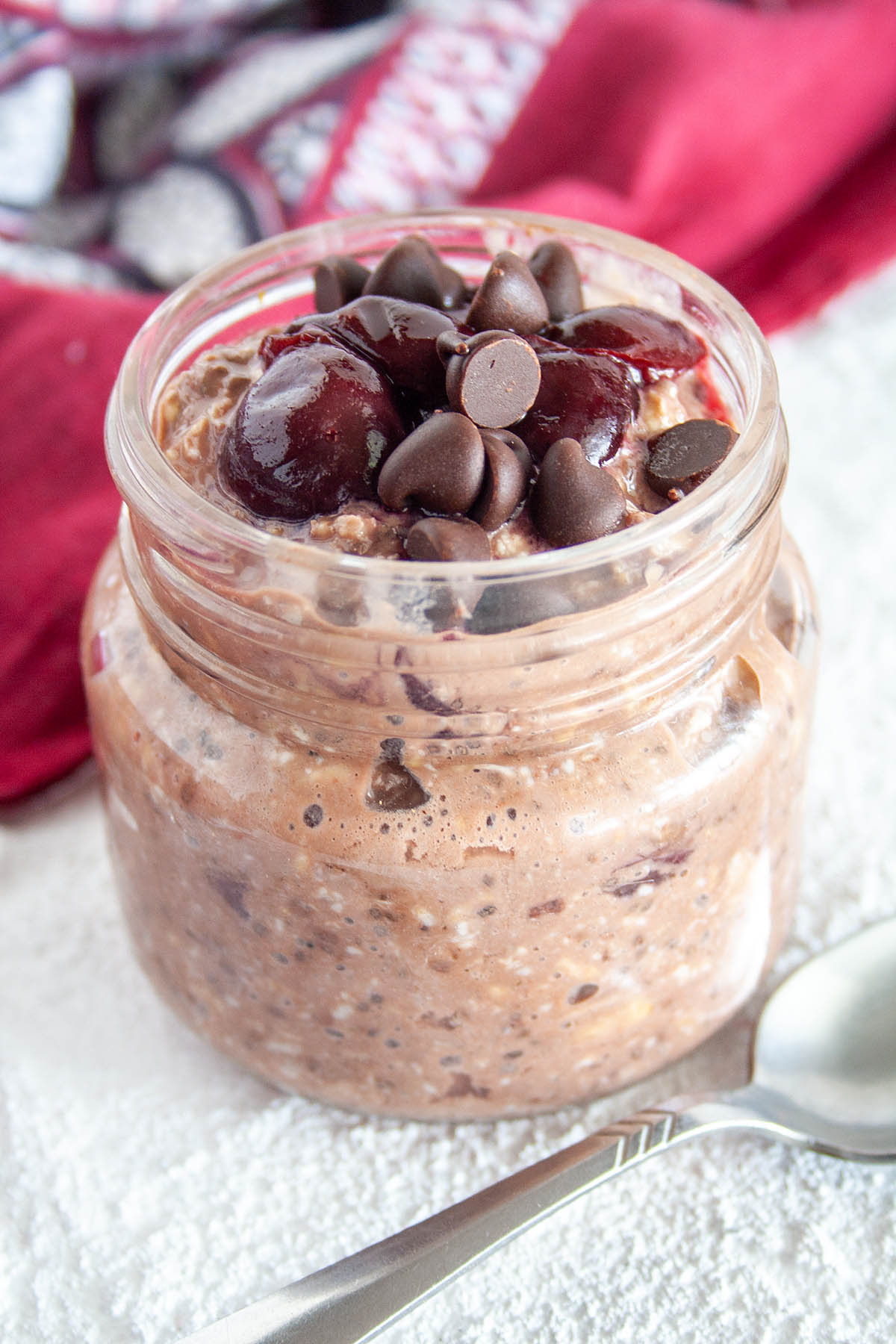 Chocolate Cherry Overnight Oats in a mason jar with spoon.