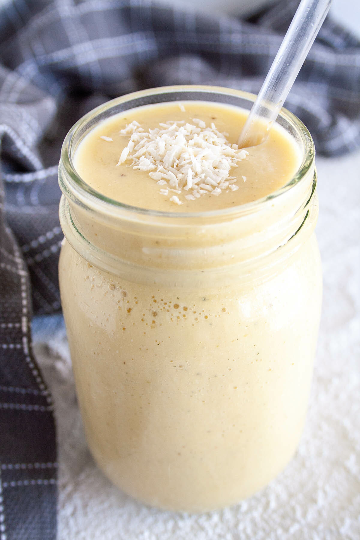 Tropical Smoothie in mason jar with coconut on top.