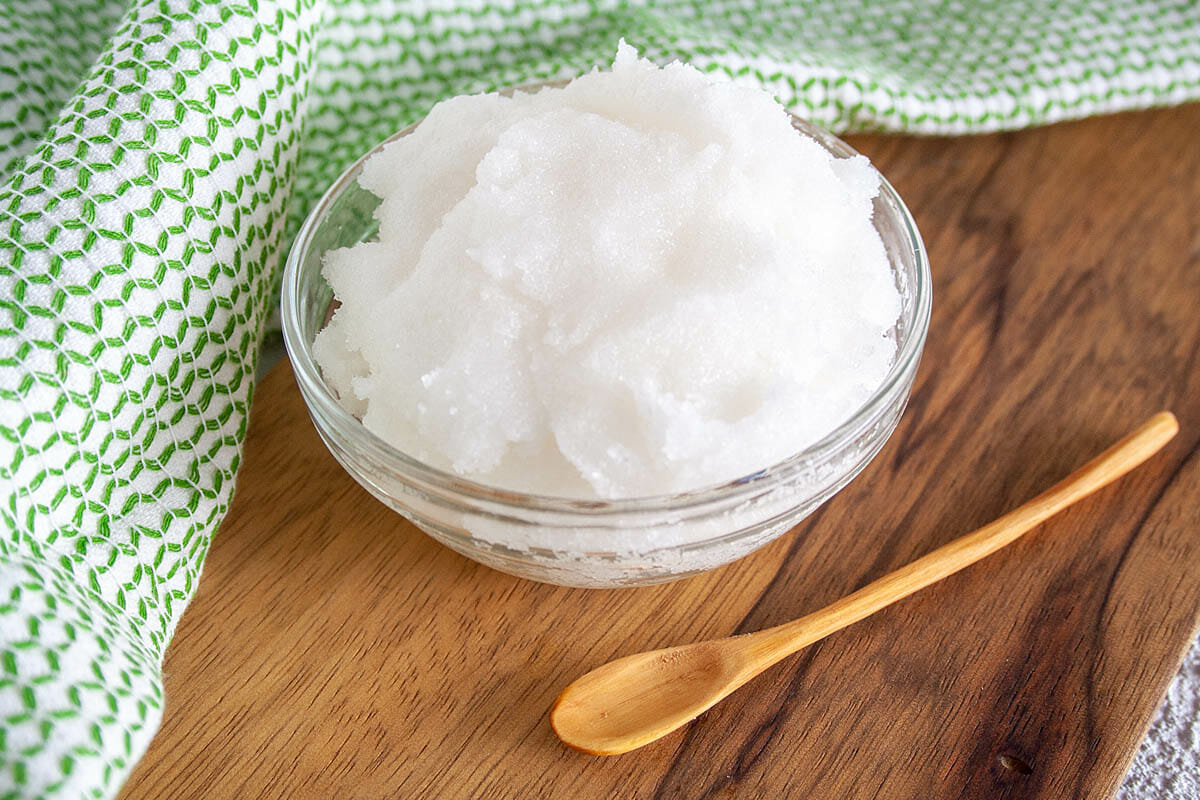 Tea Tree Oil Foot Scrub on cutting board with wooden spoon.