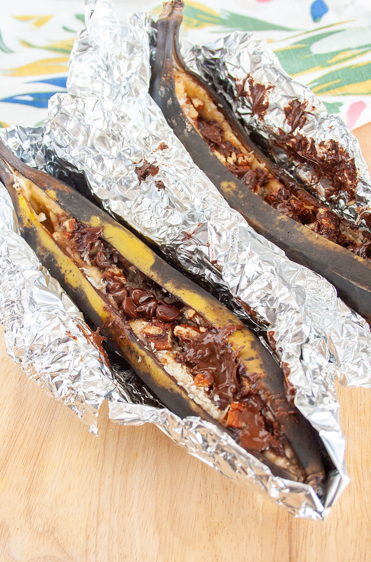 Campfire Stuffed Bananas in tinfoil on cutting board.