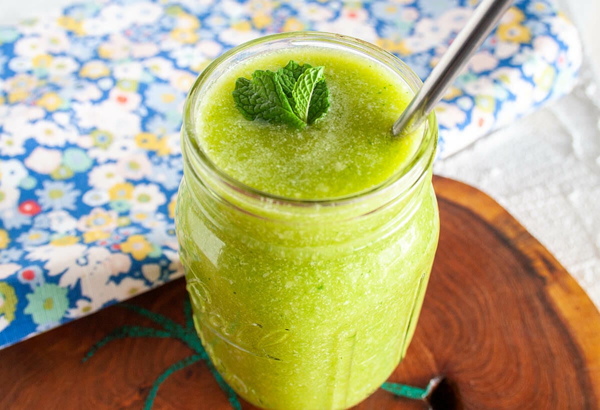 Coconut Mango Cucumber Smoothie close up with mint and straw.