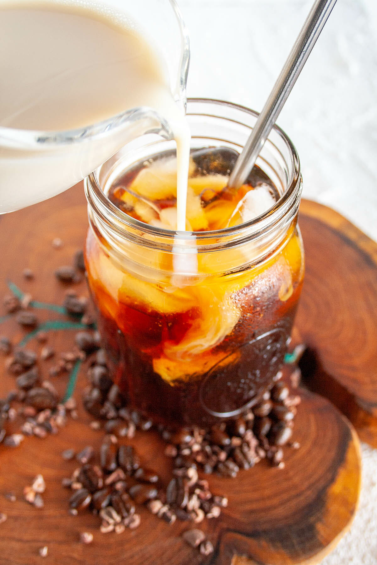 Soy milk being poured into Cold Brew Cacao Coffee.