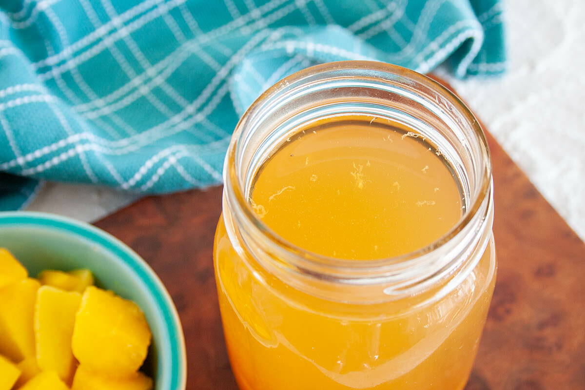 Mango Kombucha close up with ramekin of chopped mango.