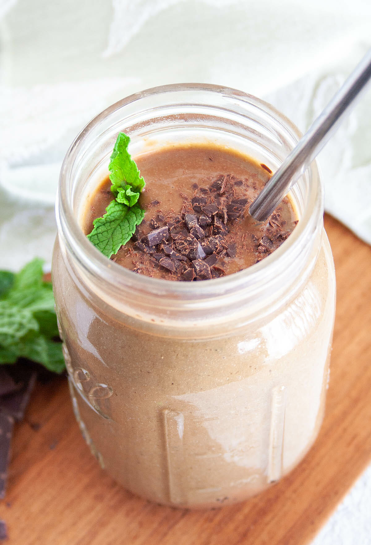 Mint Chocolate Chip Smoothie with mint leaves and chopped dark chocolate.