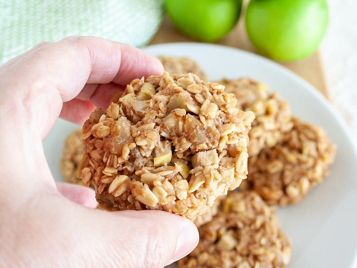 Apple Oatmeal Cookie in hand with more on a plate in the background.