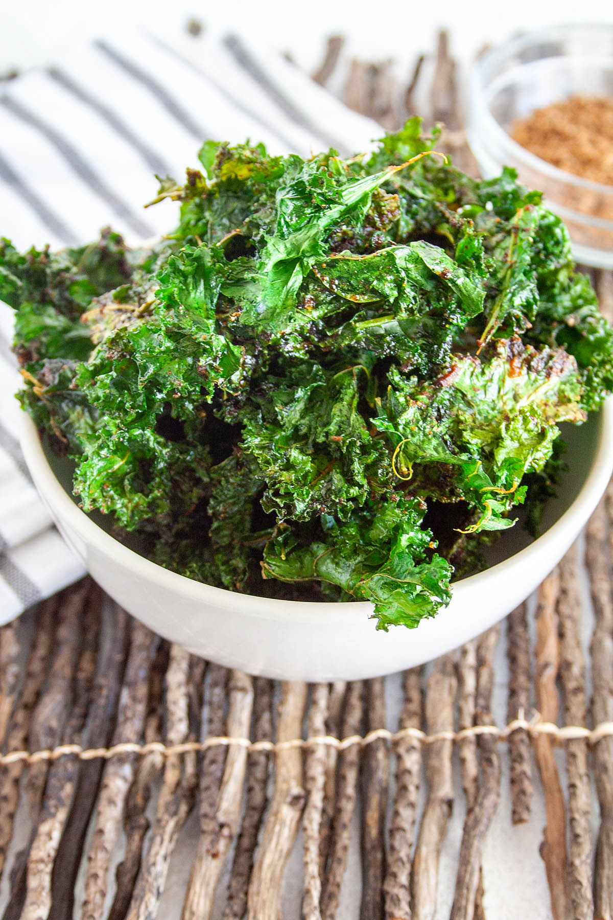 BBQ Kale Chips in a bowl with BBQ seasoning in the background.