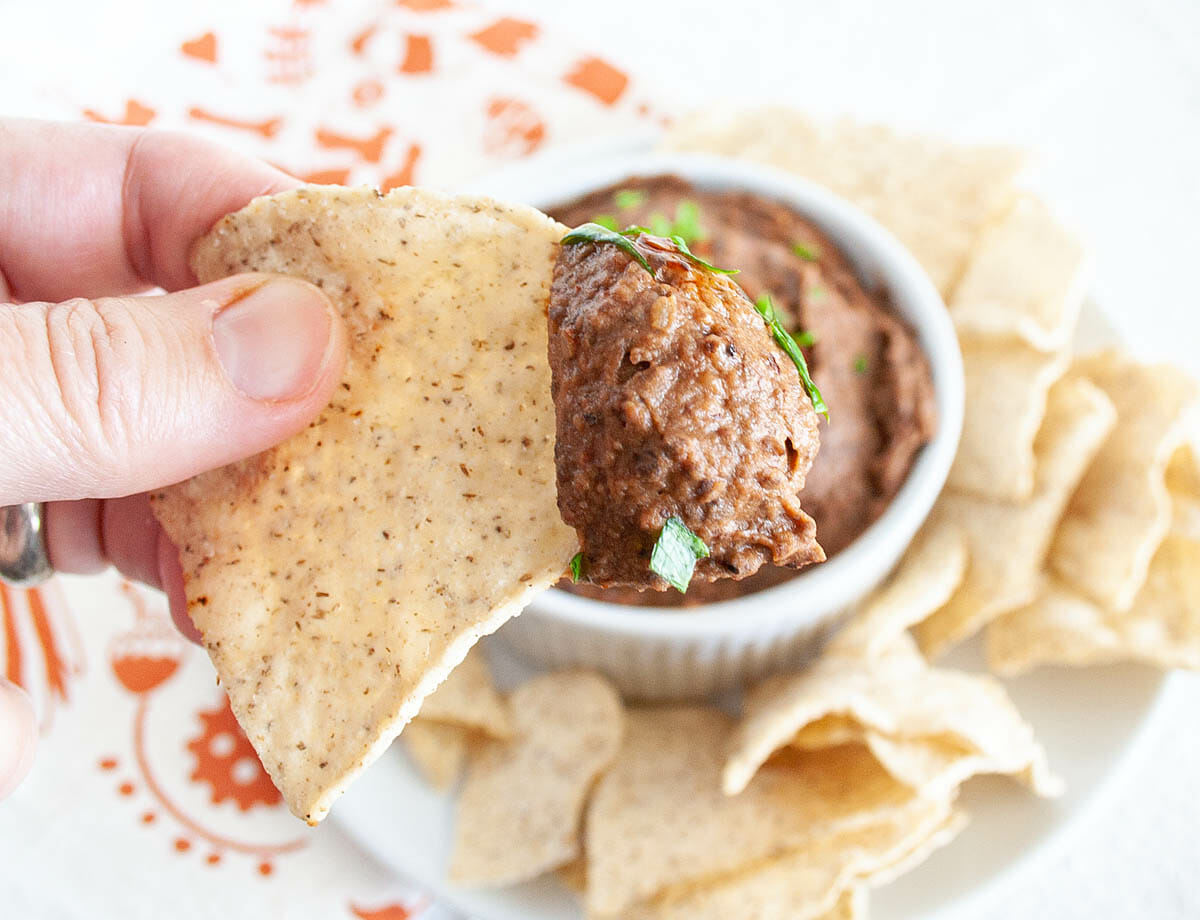 Chipotle Black Bean Dip on a tortilla chip in hand.
