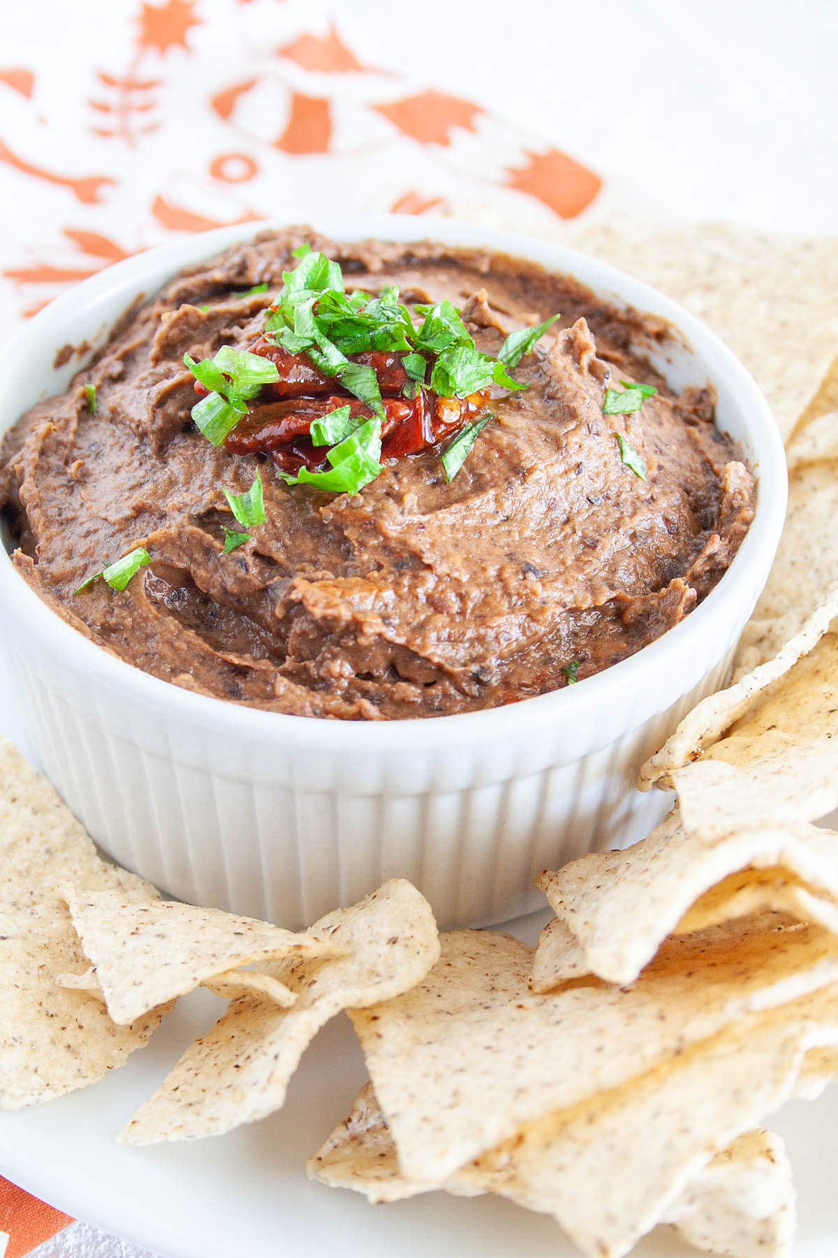 Chipotle Black Bean Dip in a ramekin on a plate with tortilla chips.