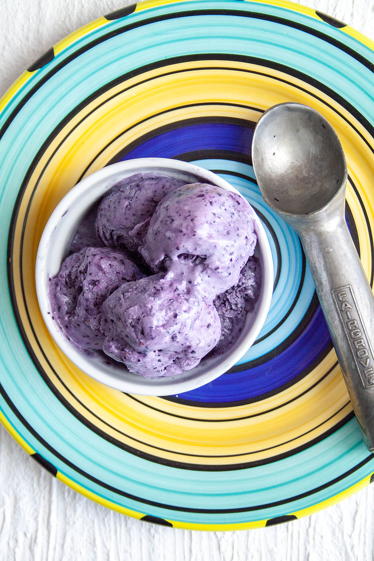 Blueberry Ice Cream with ice cream scoop on a plate.
