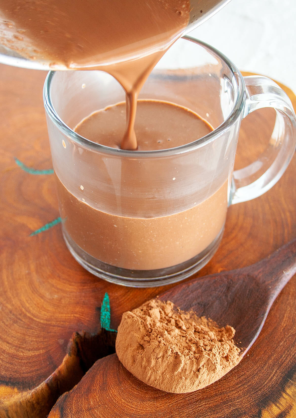 Spiced Hot Cocoa being poured into a glass mug.