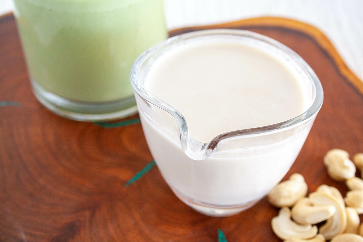 Cashew Milk in pitcher with mug of matcha tea.