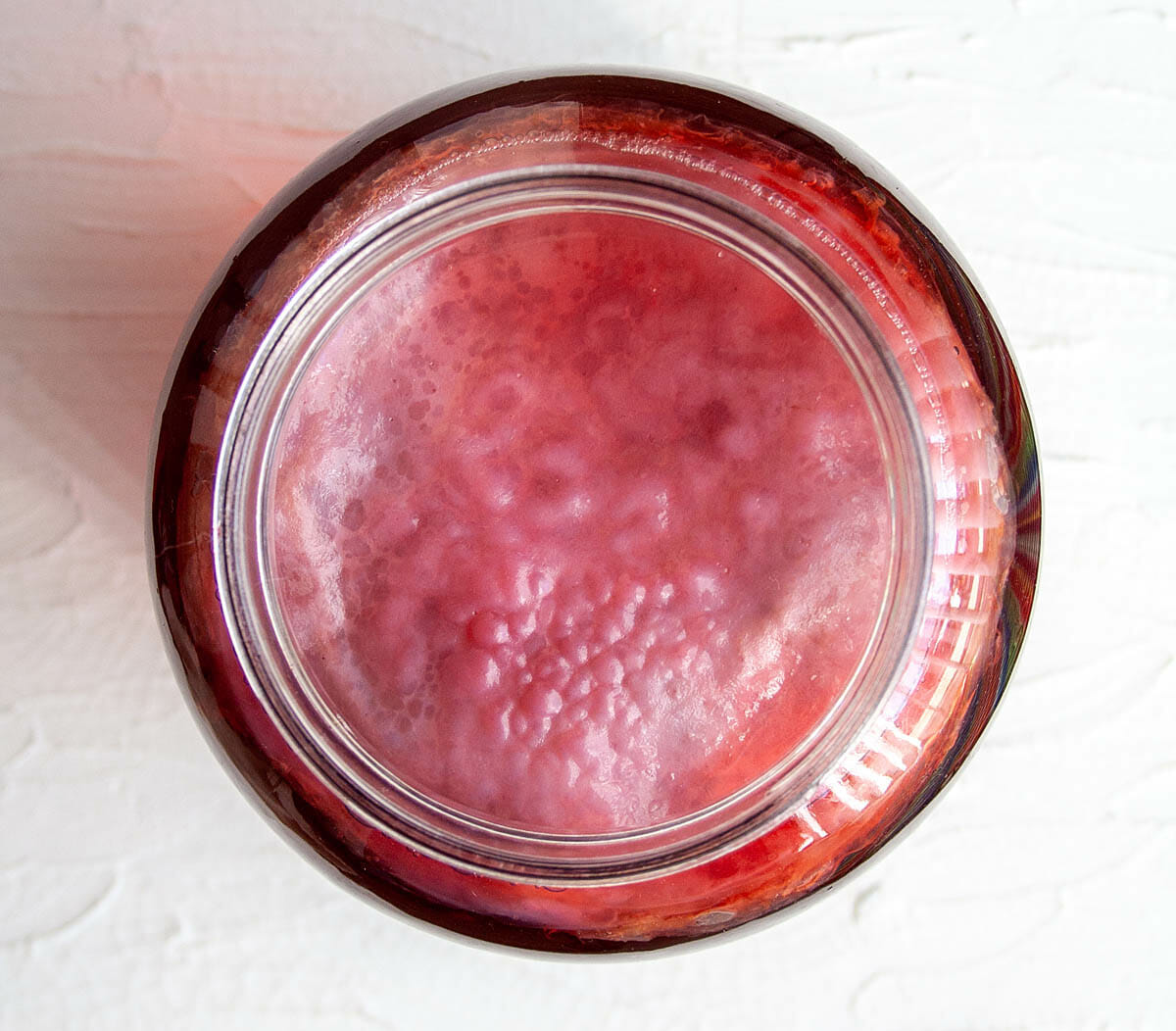 Kombucha scoby in gallon sized mason jar with hibiscus tea.