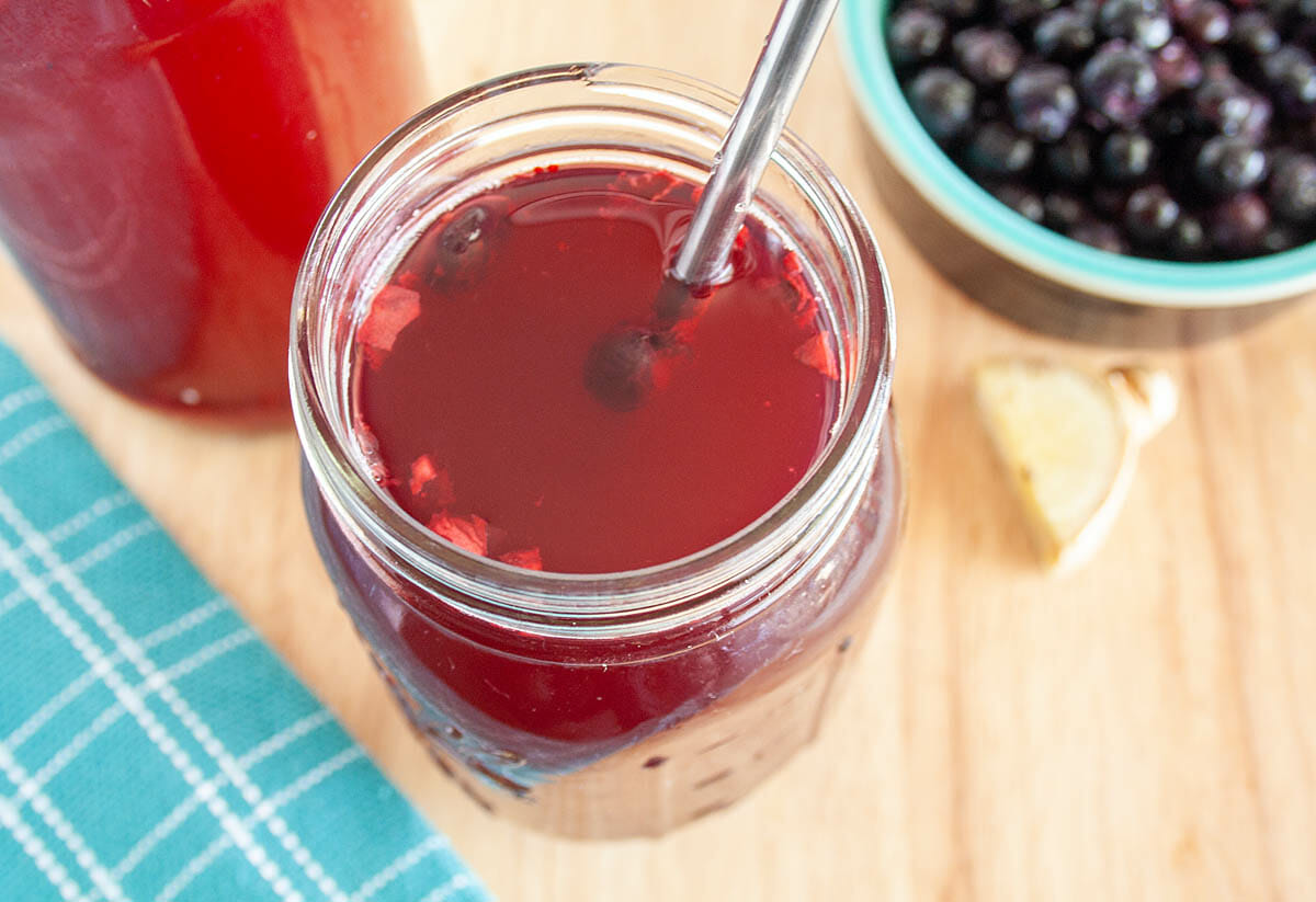 Blueberry Ginger Kombucha in mason jar with blueberries and ginger in background.