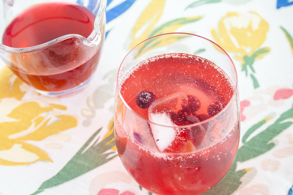 Blueberry Shrub in club soda with shrub in background.