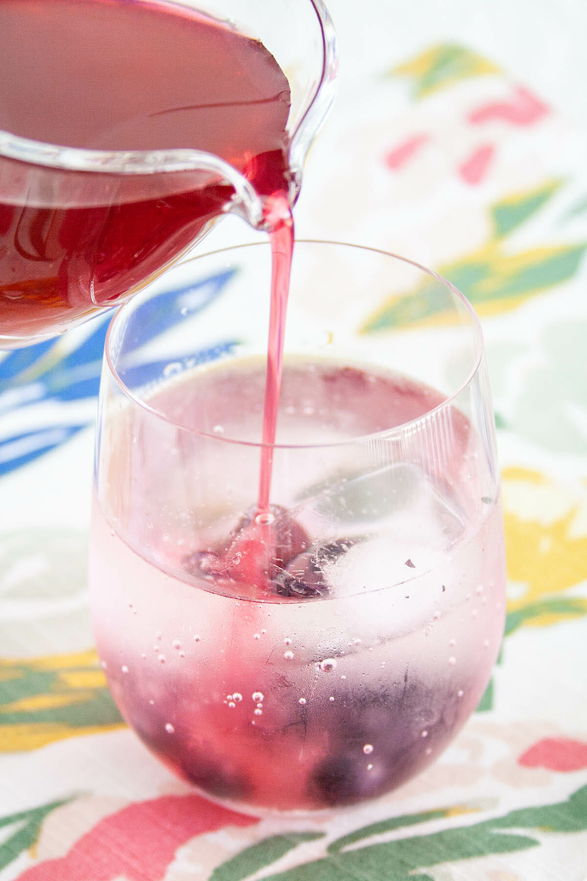 Blueberry Shrub being poured into a glass with club soda.