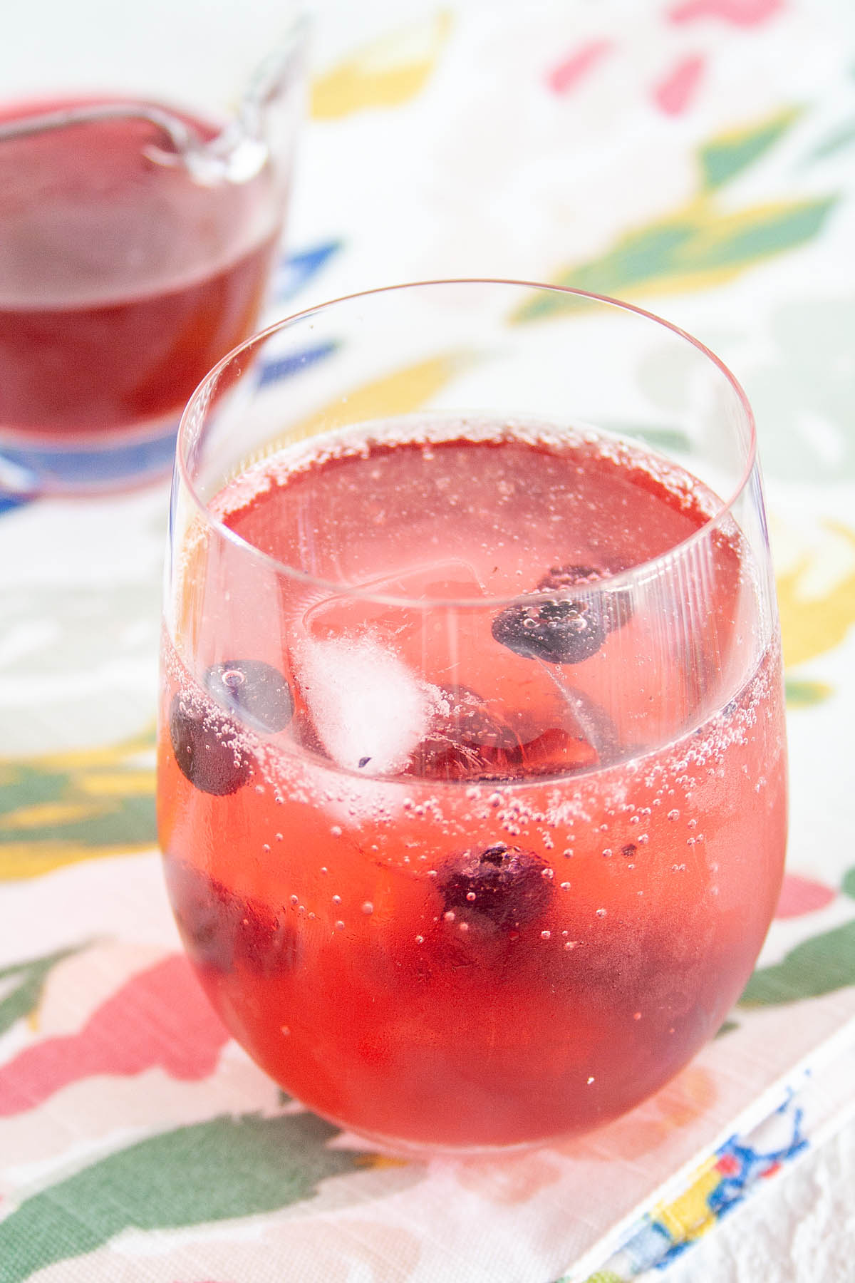 Blueberry Shrub in club soda with shrub in background.