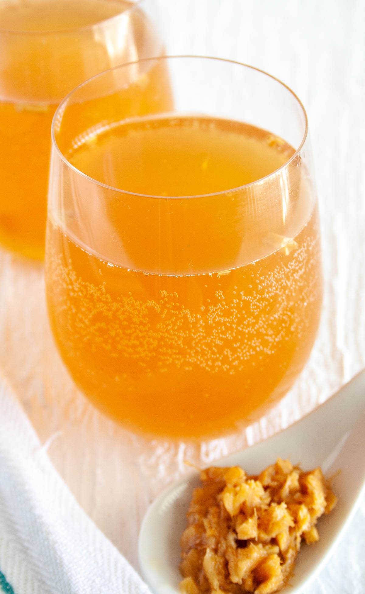 Ginger Kombucha with fresh ginger in foreground.