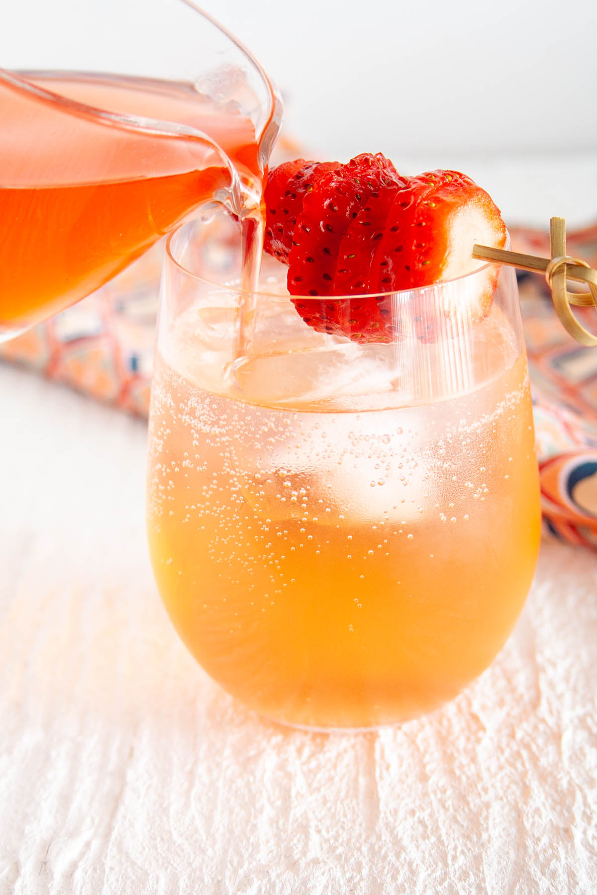 Strawberry Shrub being poured into glass with club soda.