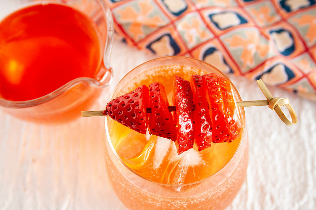 Strawberry Shrub with club soda in wine glass. Shrub in pitcher.