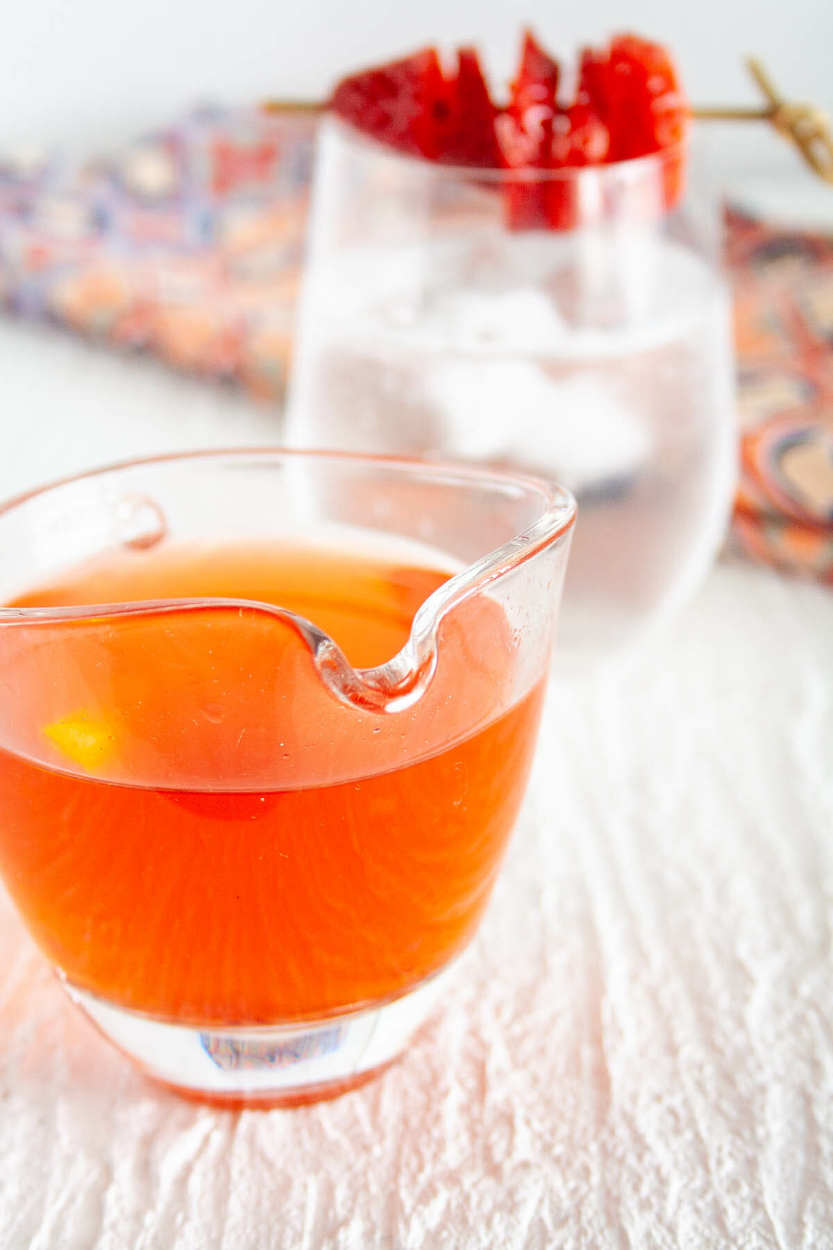 Strawberry Shrub in a pitcher with a glass of club soda in background.