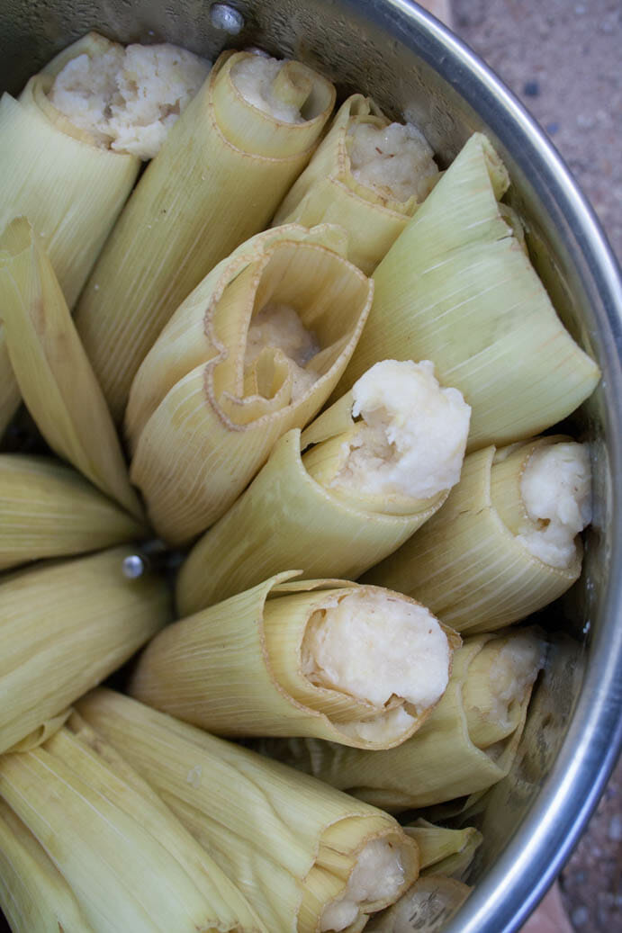 Tamales being steamed in a large pot.