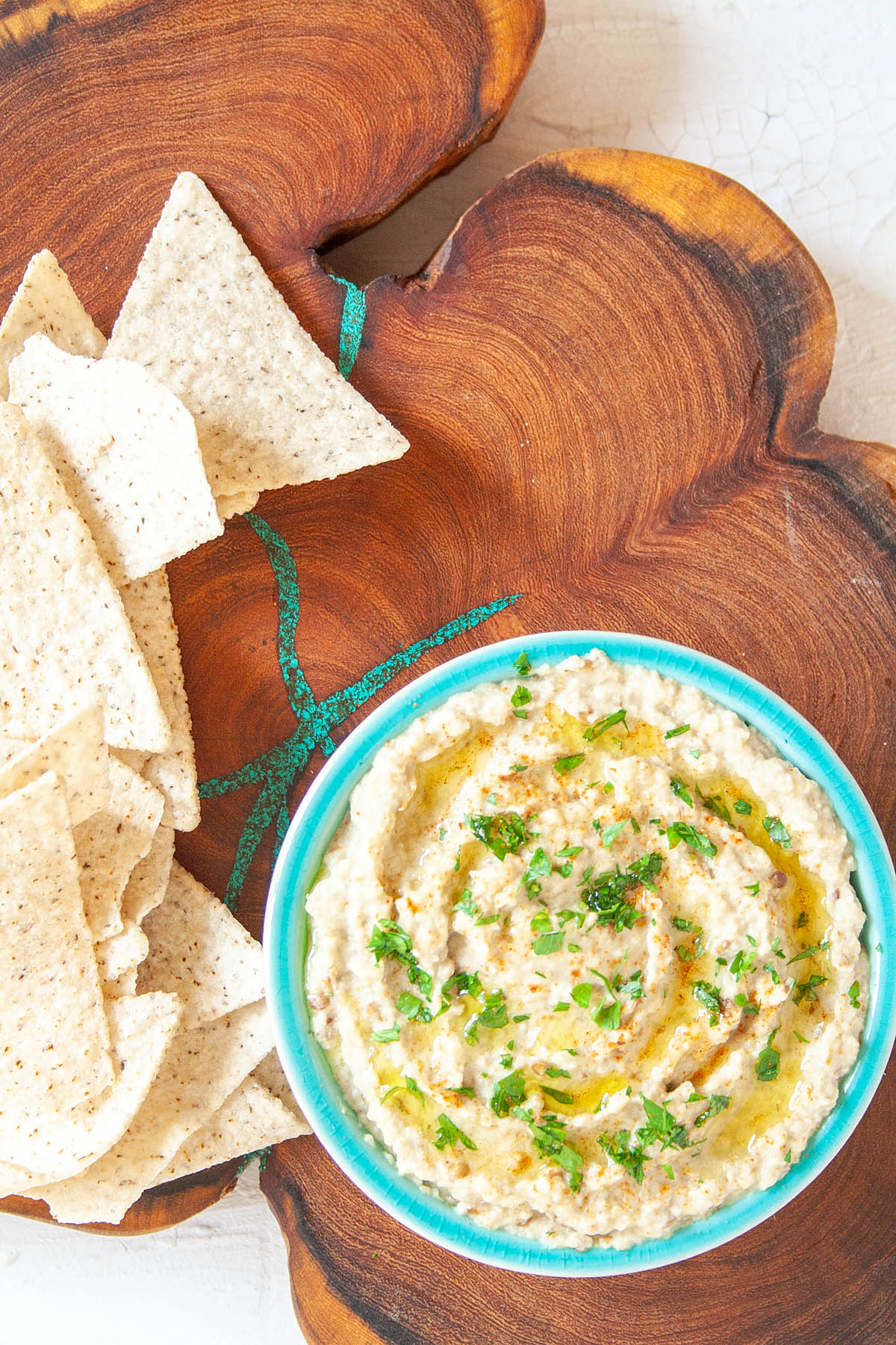 Baba Ghanoush in ramekin on cutting board with tortilla chips.