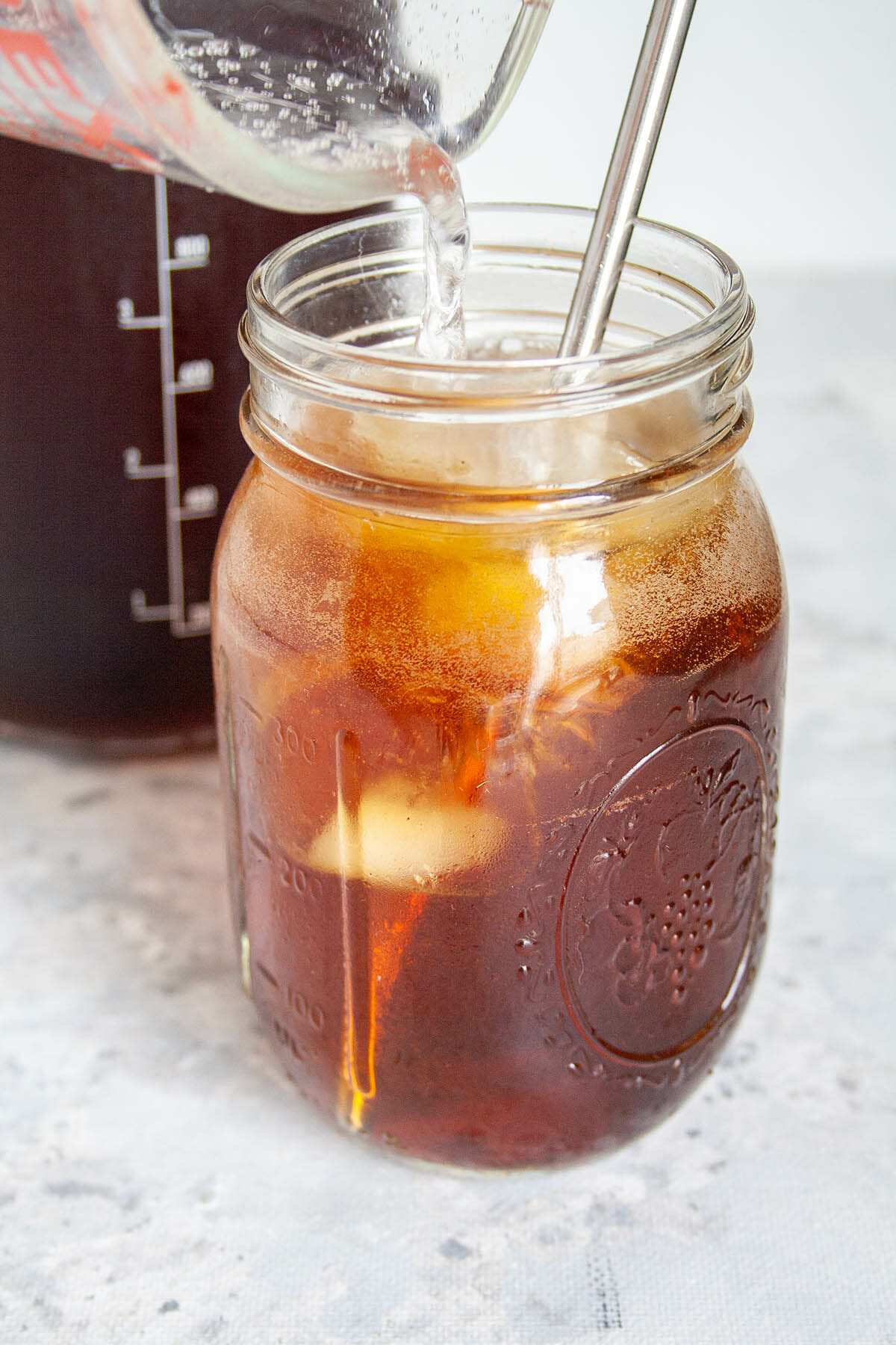 Club soda being poured into a mason jar with coffee.