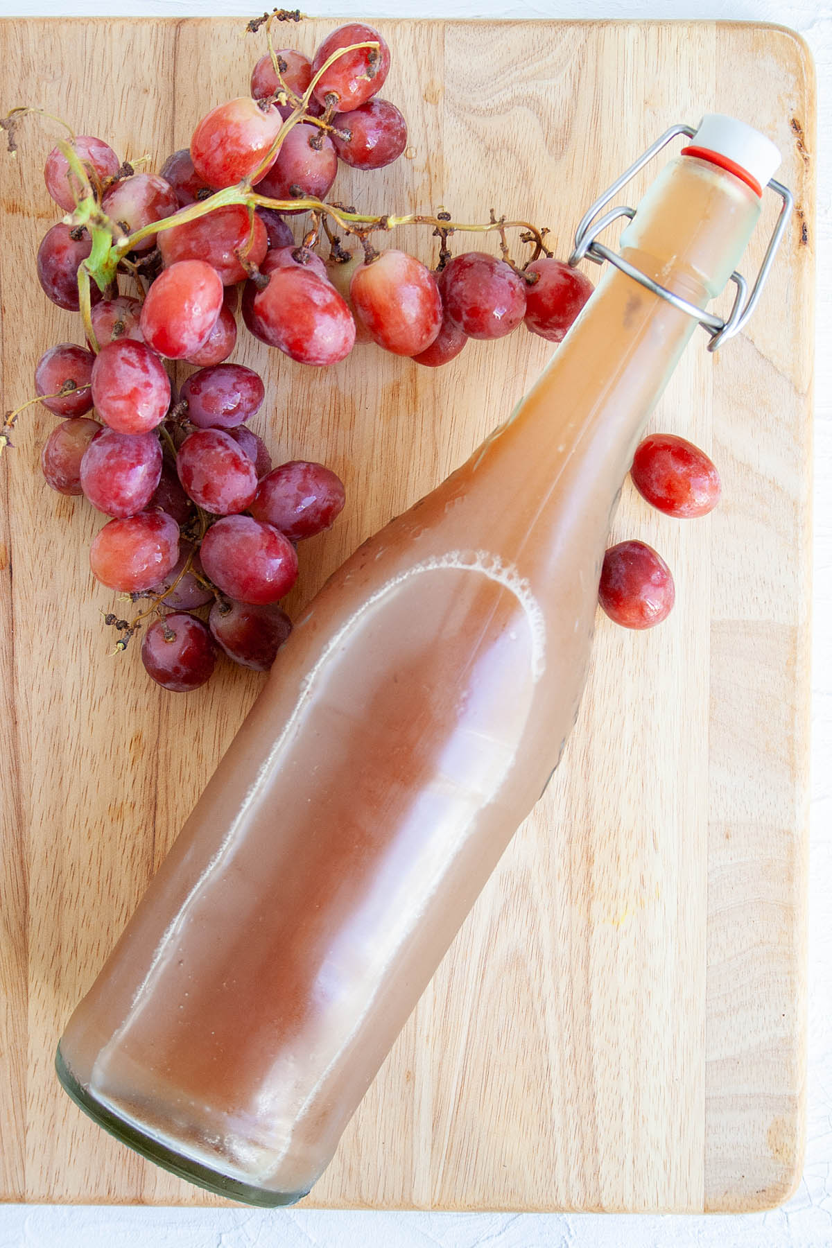 Grape Kombucha in bottle with grapes.