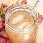 Grape Kombucha in a mason jar with a straw.