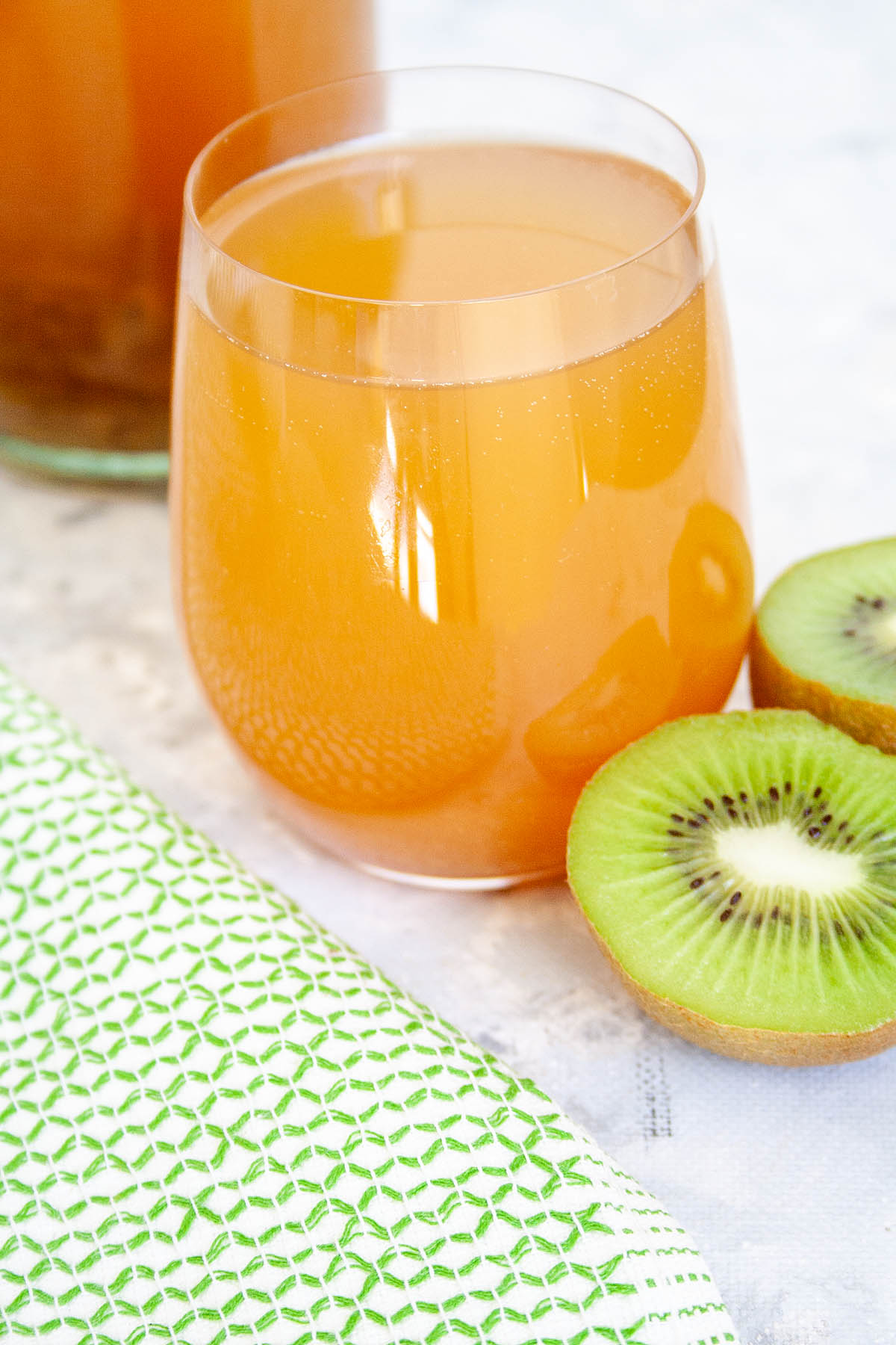 Kiwi Kombucha in glass with kiwis.