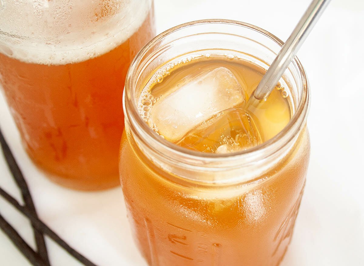 Vanilla Kombucha in mason jar with straw next to bottle.