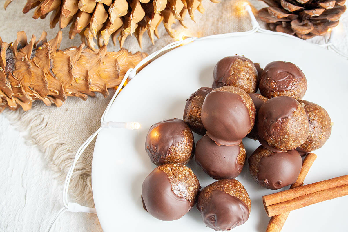 Gingerbread Energy Bites on a plate with cinnamon sticks.