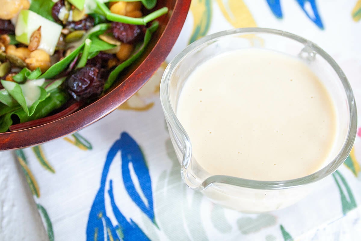 Maple Tahini Dressing in pitcher next to salad.