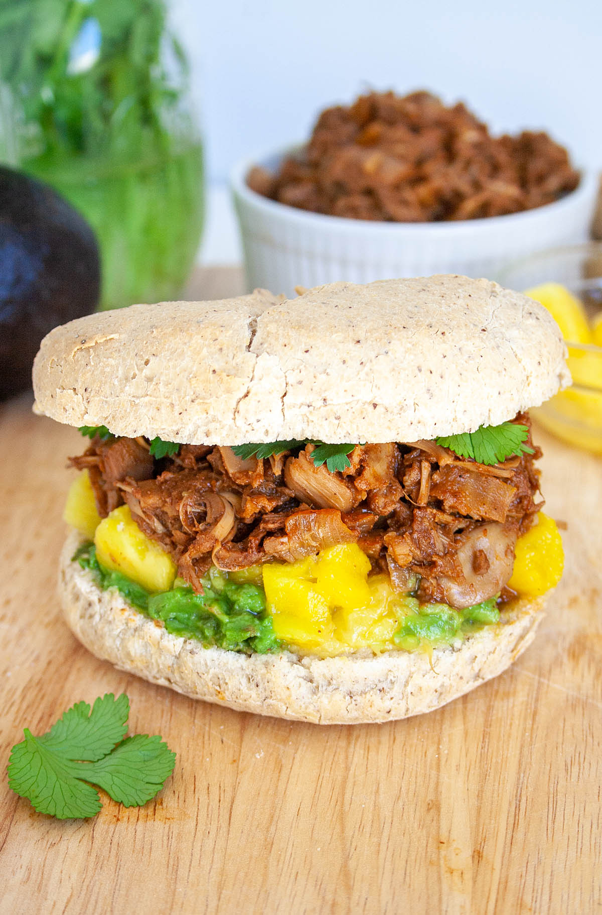 BBQ Jackfruit Sandwich on a cutting board with jackfruit in the background.