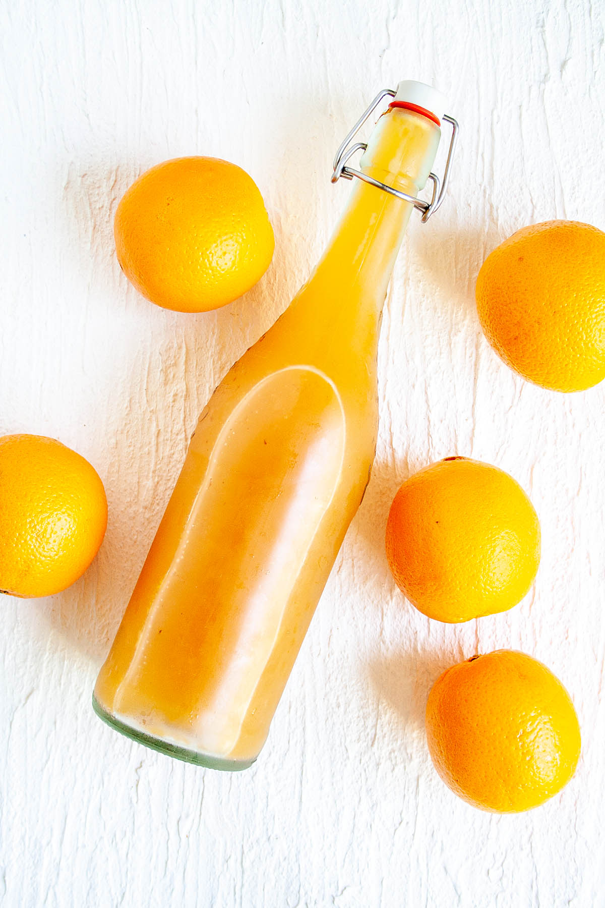 Orange Kombucha in bottle with oranges.