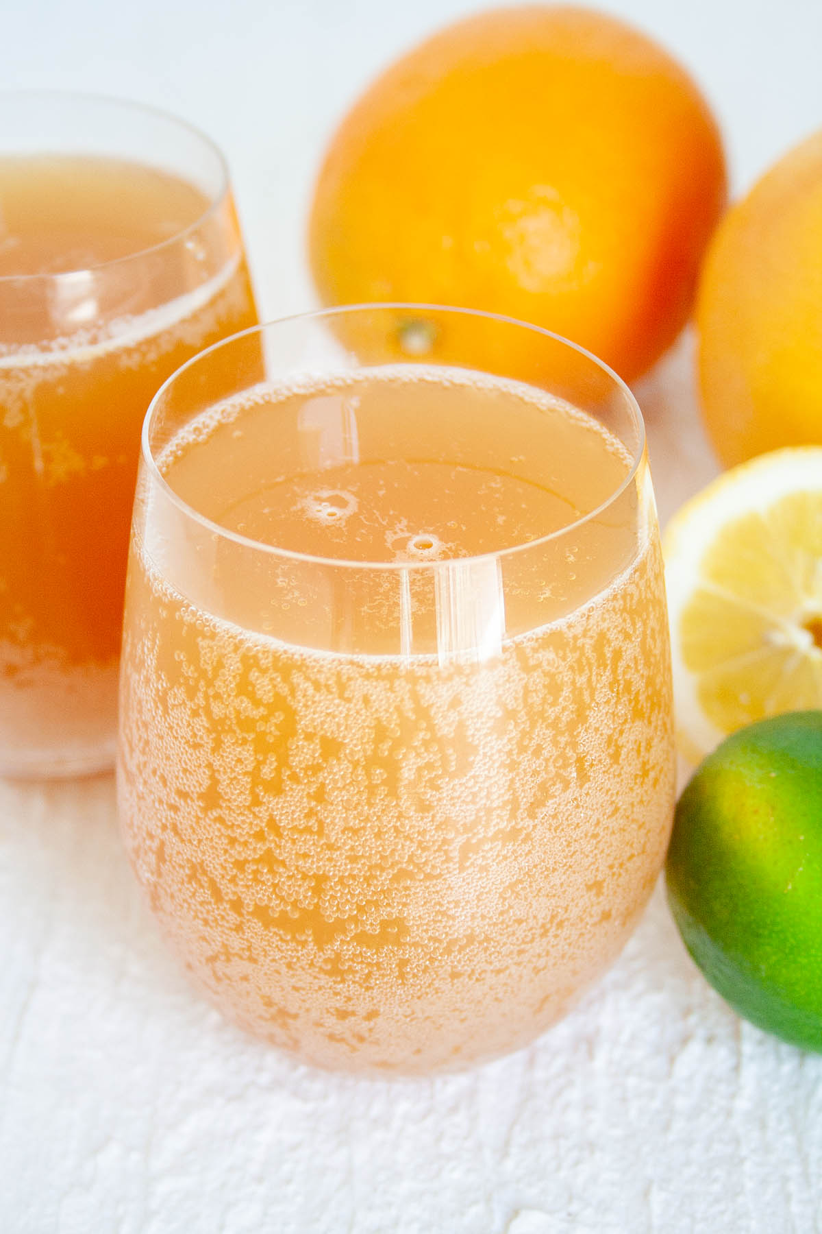 Citrus Kombucha in two glasses next to citrus fruit.
