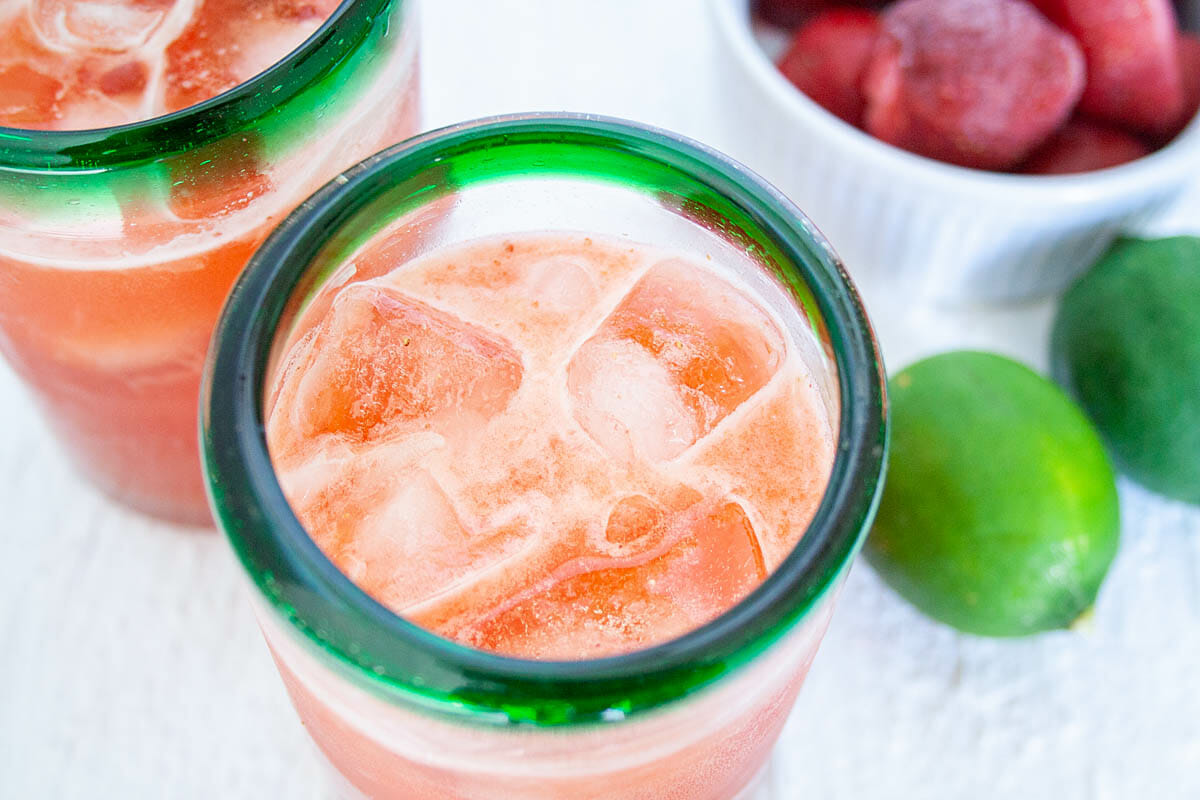 Strawberry Limeade in two glasses with strawberries and limes in the background.