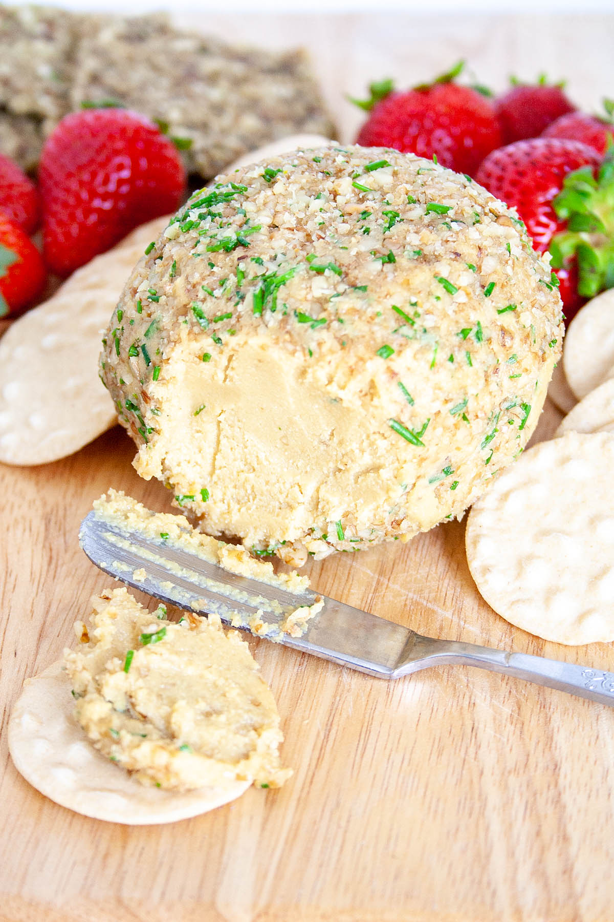 Vegan Cheese Ball on cutting board and spread on cracker.
