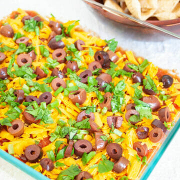 Vegan 7 Layer Dip in a baking dish with tortilla chips in the background.