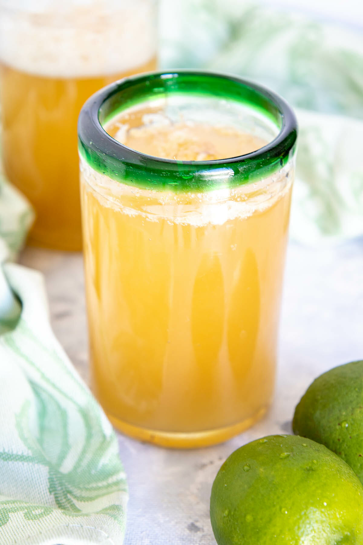 Lime Green Tea Kombucha in a glass with limes.