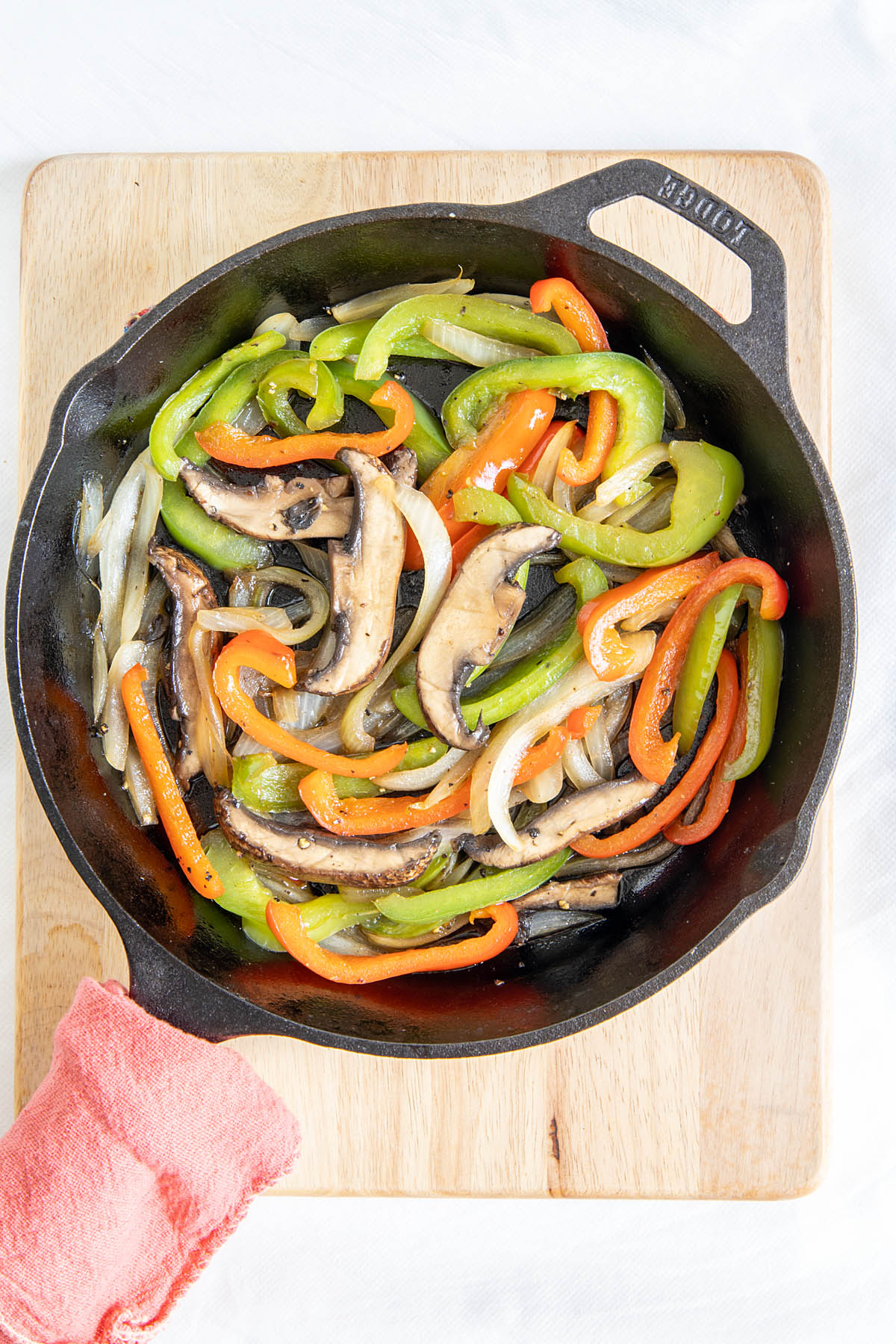 Onions, bell peppers, and portobello mushrooms in a cast iron skillet.