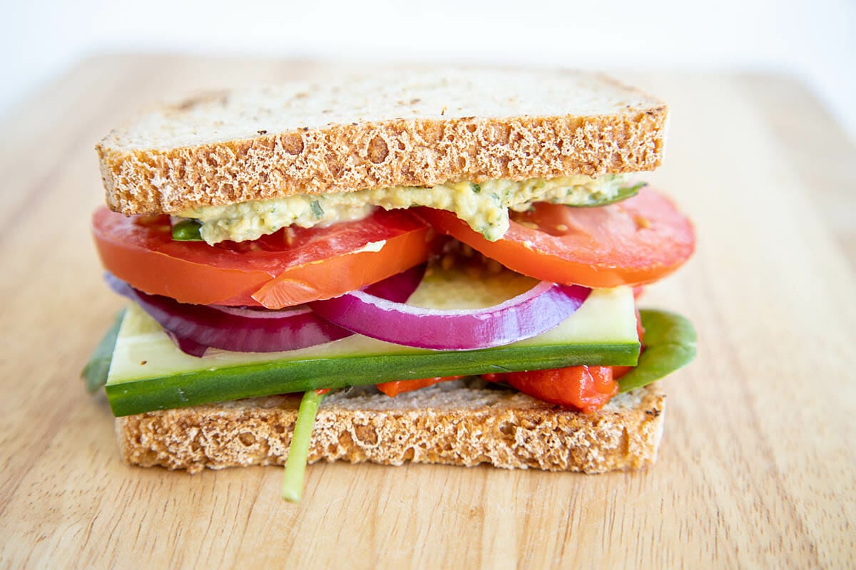 Veggie Sandwich with Hummus on cutting board.