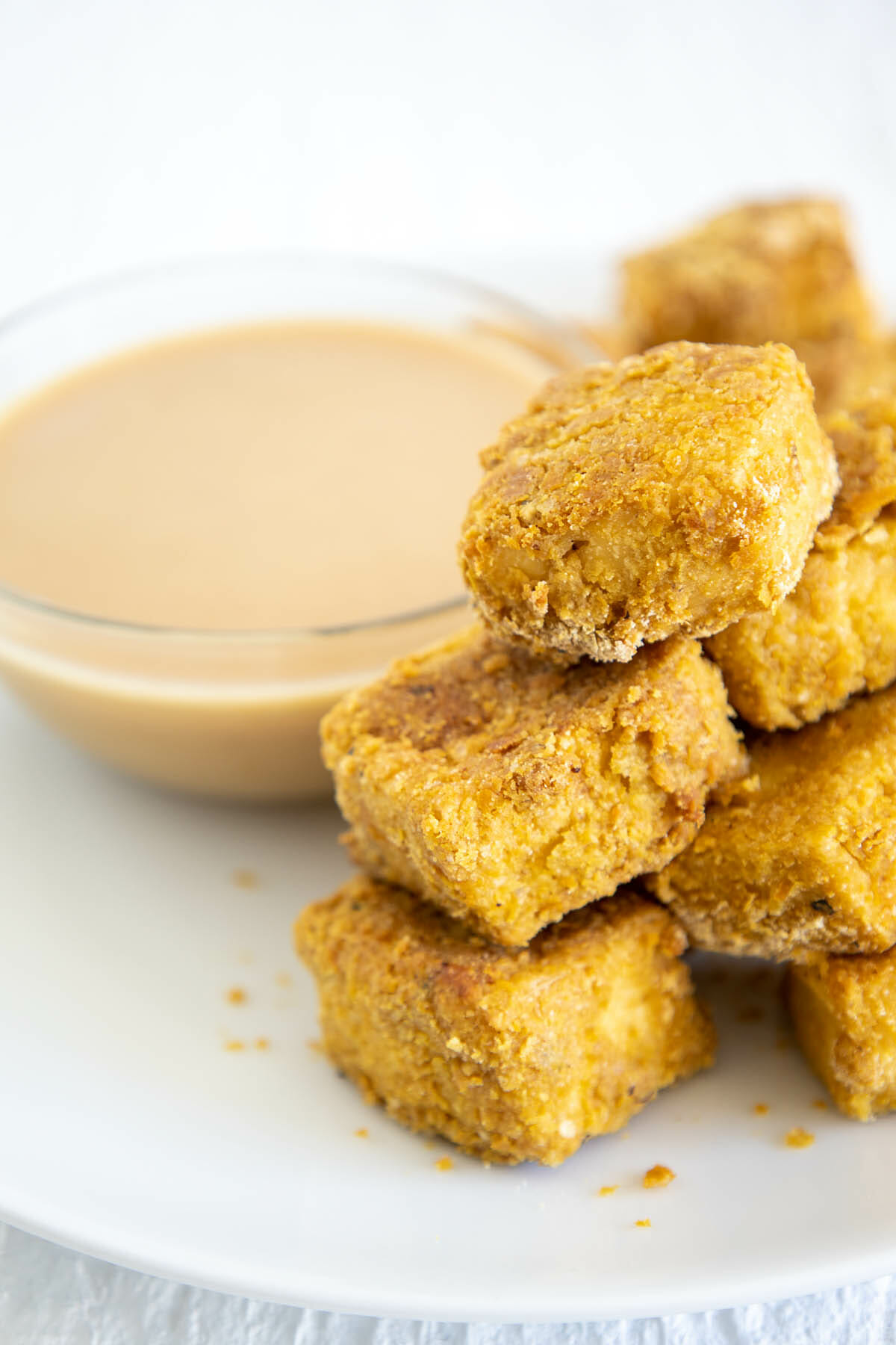 Baked Tofu Nuggets on a plate next to vegan Honey Mustard Dressing.
