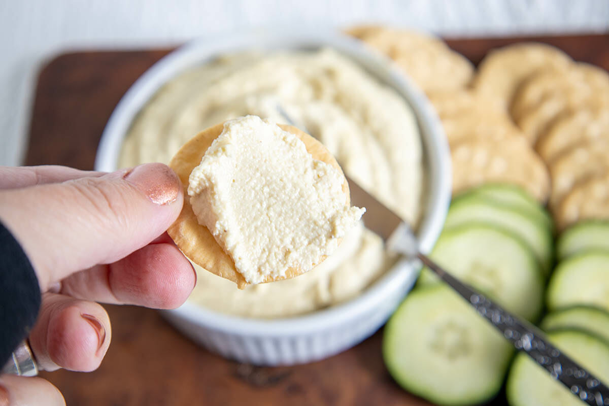 Cracker with vegan cream cheese in hand.
